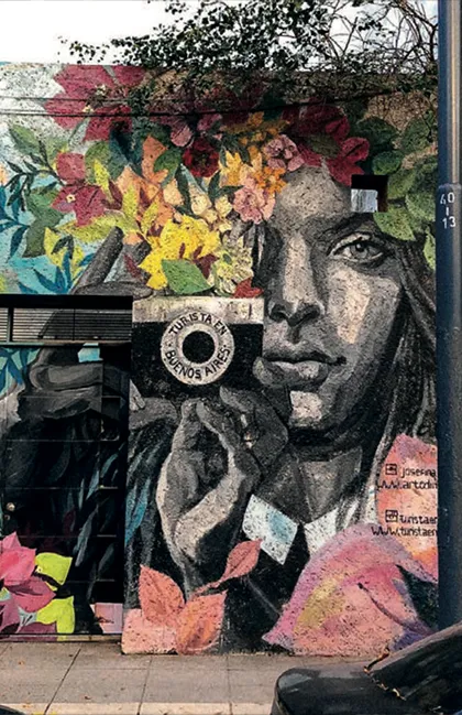 Mural colorido en pared con rostro humano y flores.